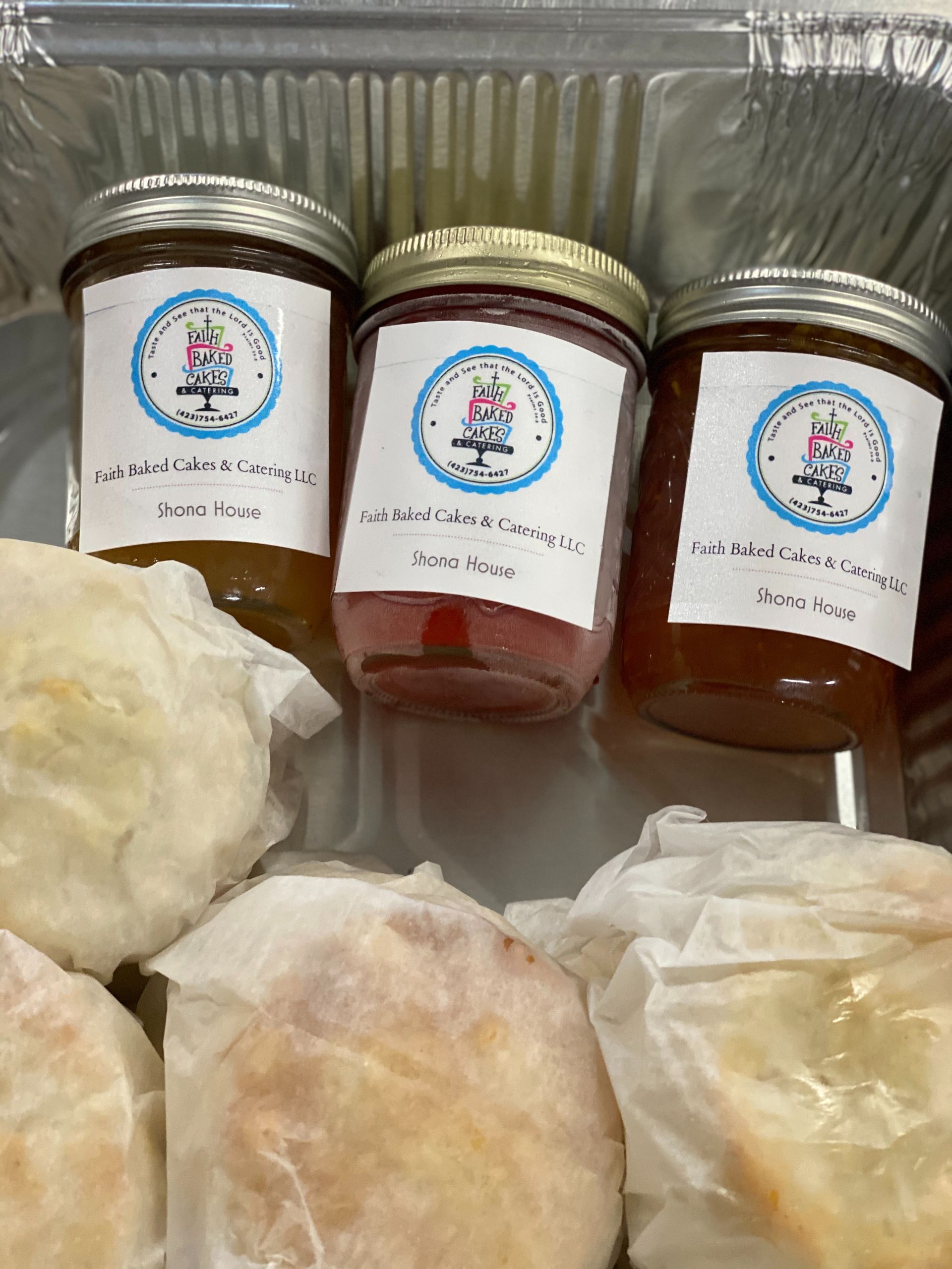 Three labeled condiment jars and three wrapped baked goods in a plastic container