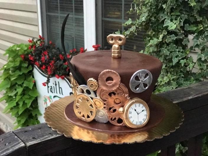 Steampunk-style cupcake display with gears and a clock on a gold tray beside a faith planter outdoors