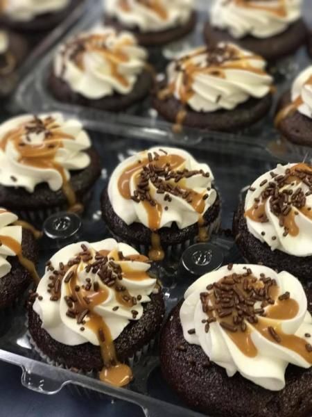 Chocolate cupcakes with white frosting, caramel drizzle, and chocolate shavings in a tray