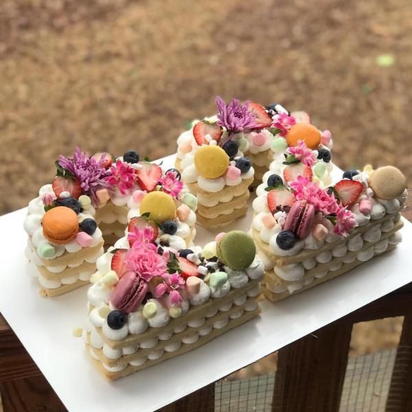 Decorated number-shaped cake topped with colorful flowers and fruit on a white board