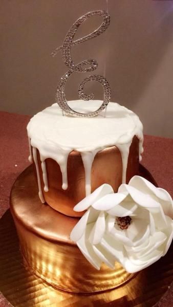 White drip cake with silver number 6 topper and white flower decoration on a copper stand