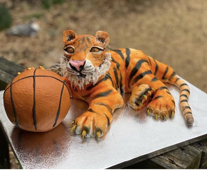 Tiger figurine lounging beside a basketball on a metal surface outdoors