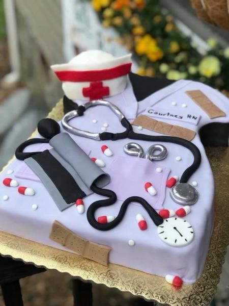 Nurse-themed decorated cake with stethoscope, syringe, pills, and a nurse cap on top