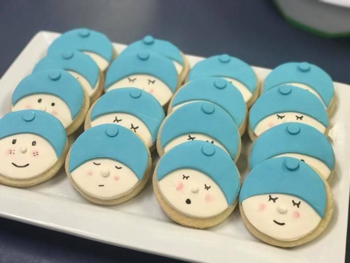 Tray of blue-and-white frosted cookies with smiling faces arranged in rows