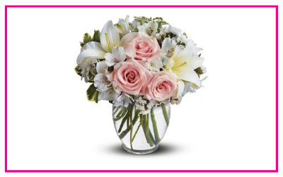 Pink roses and white lilies arranged in a clear glass vase on a white background