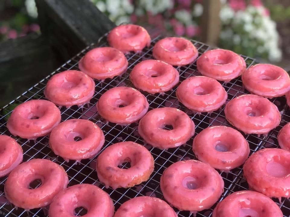 Pink frosted donuts arranged on a cooling rack at a bakery