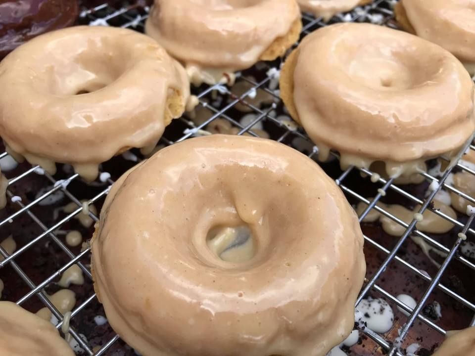 Glazed donuts cooling on a wire rack, one in the foreground and three behind.