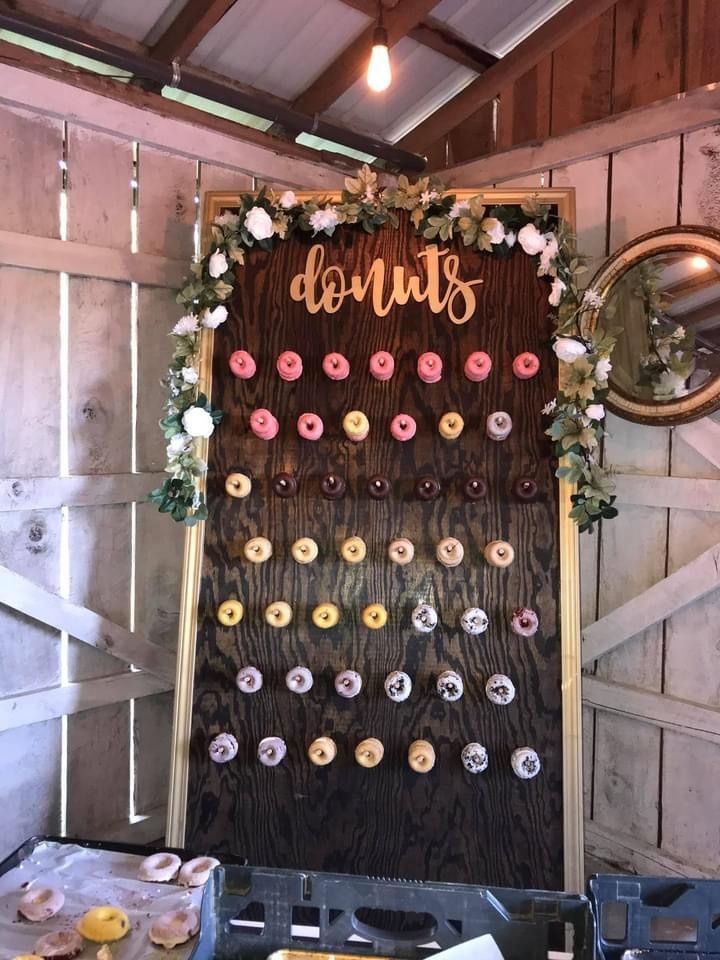 Rustic donut wall display with pink and tan donuts under floral greenery and a “donuts” sign