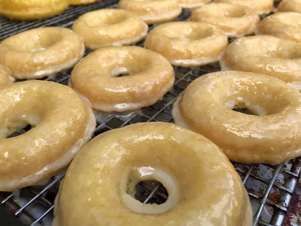 Glazed ring doughnuts cooling on a wire rack, with one close-up in the foreground