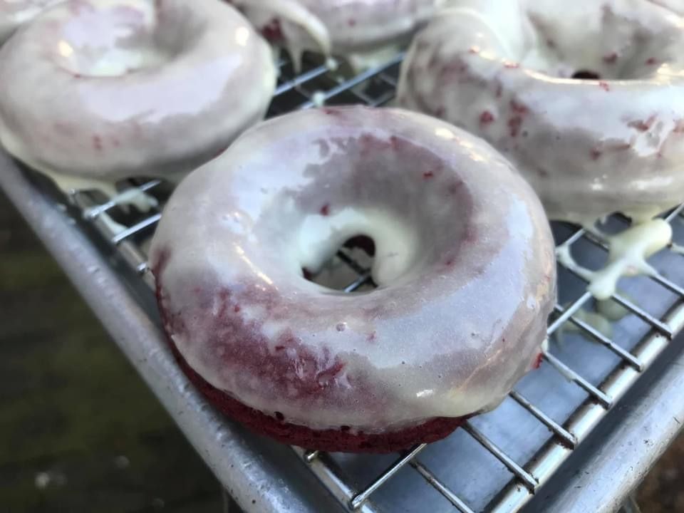 Glazed donuts cooling on a wire rack, with one in the foreground.