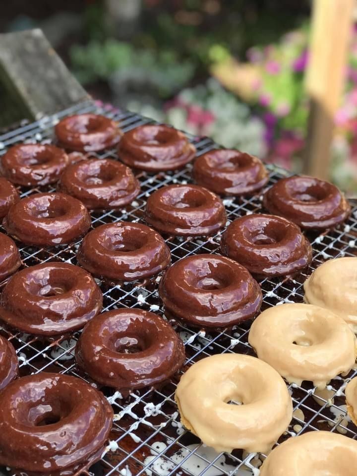 Chocolate and vanilla-glazed donuts cooling on a wire rack outdoors