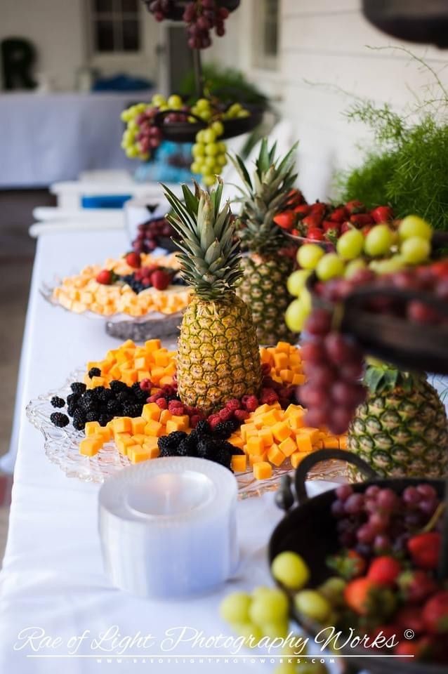 Pineapple centerpiece on a dessert table with fruit platters and assorted colorful fruit baskets