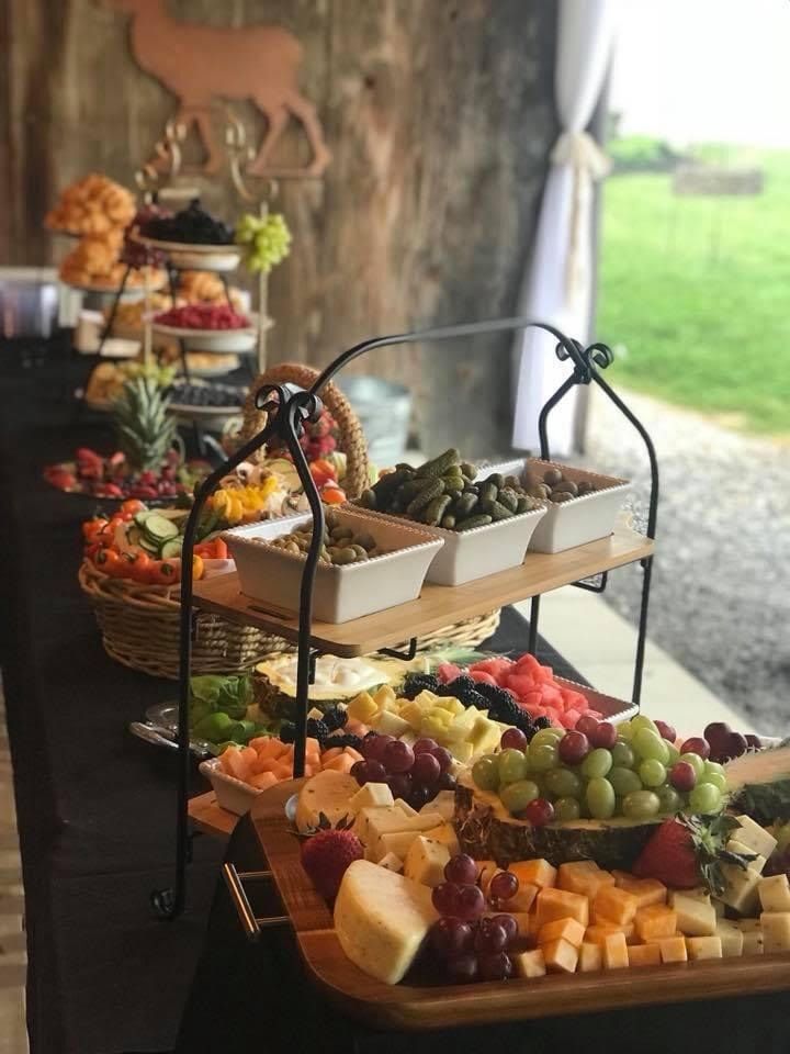 Buffet table with assorted fruit, cheese, and appetizers in a rustic indoor-outdoor event setting