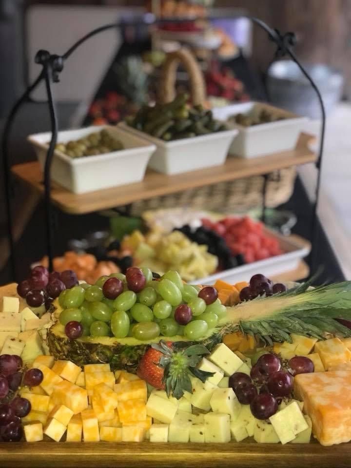 Fruit and cheese platter with grapes, melon cubes, and a tray of appetizers on a tiered stand