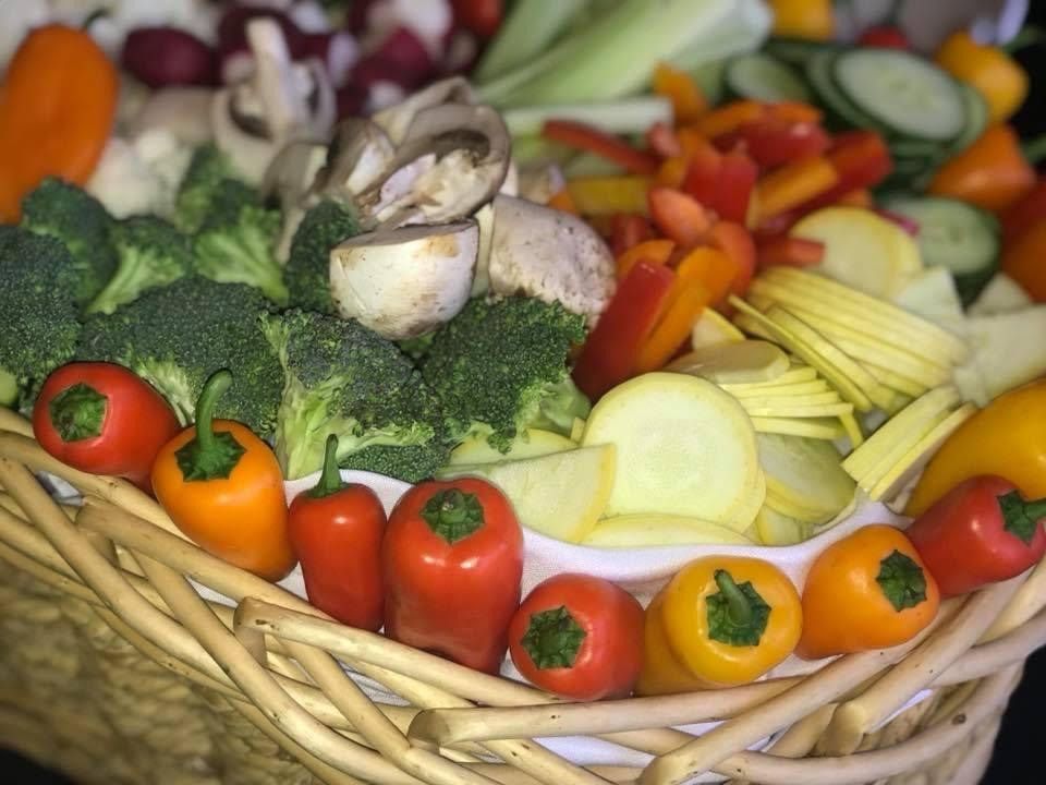 Basket of assorted fresh vegetables, including broccoli, peppers, tomatoes, onions, and carrots