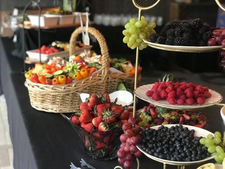 Assorted fresh fruit displayed on a market table, including strawberries, grapes, blackberries, and melon