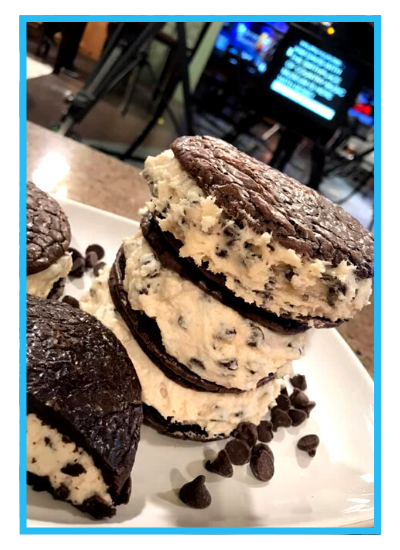 Stack of chocolate chip ice cream sandwiches on a plate with scattered chips on a table