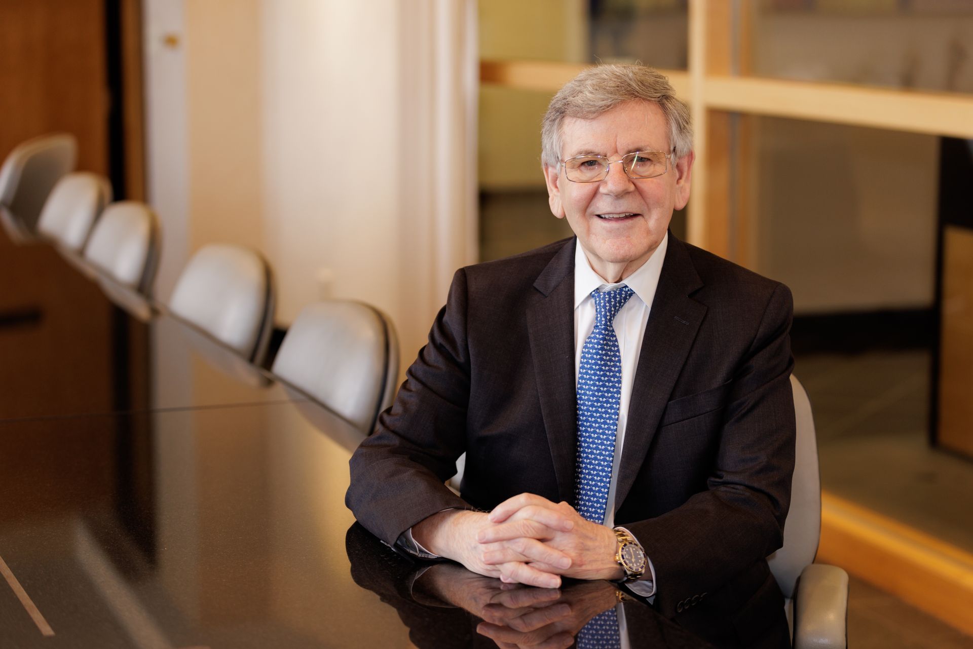 A man in a suit and tie is sitting at a conference table.