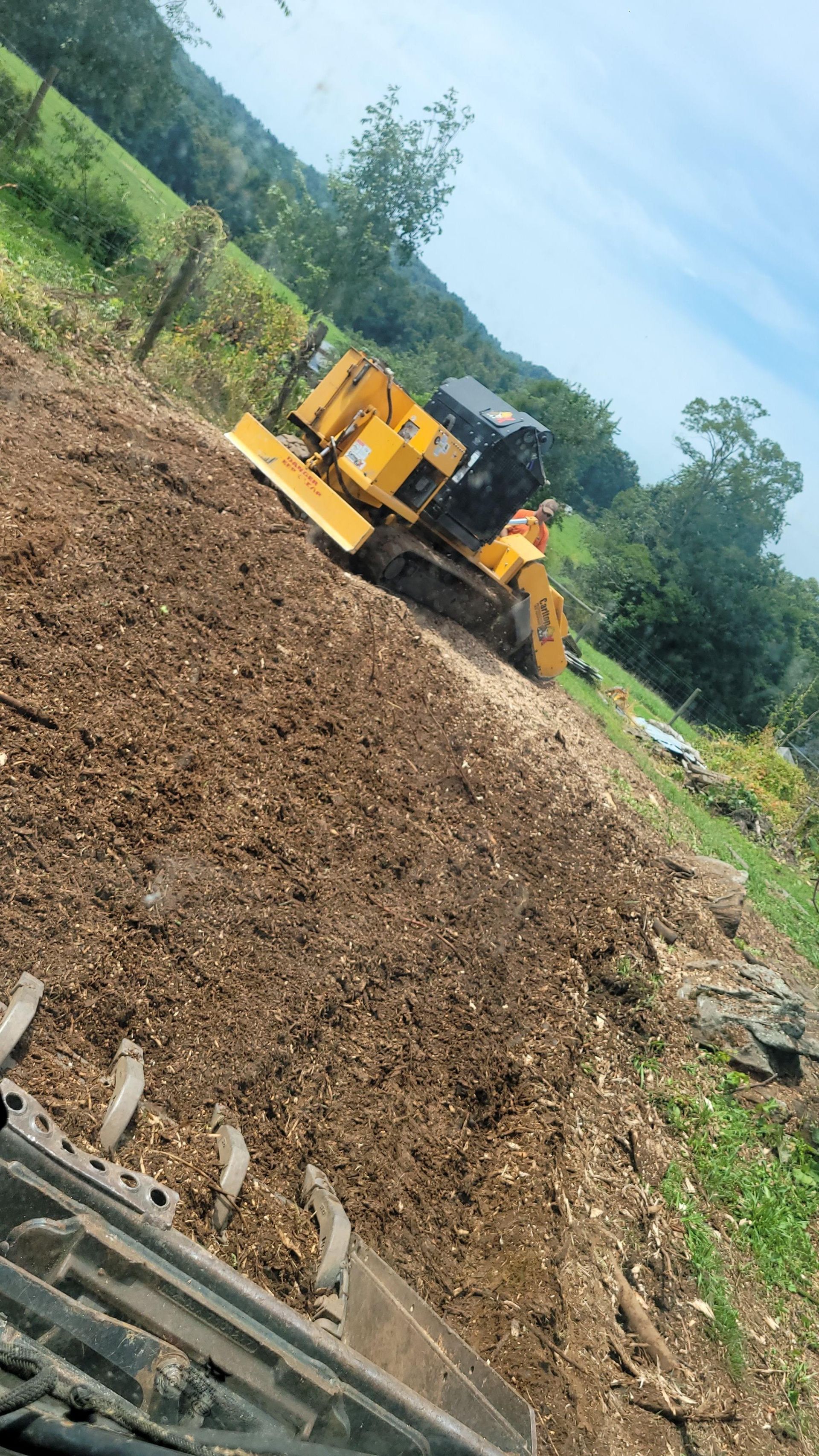 a yellow stump grinder is sitting on top of a pile of dirt