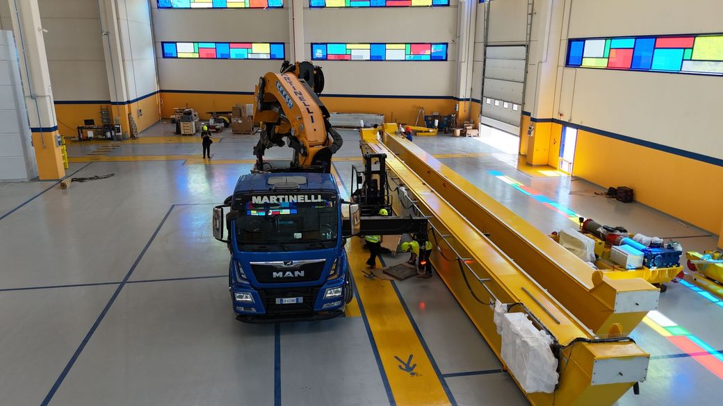 Robot autonomo blu in un laboratorio al coperto, accanto a una lunga barriera gialla e ai marcatori dell'area di prova.