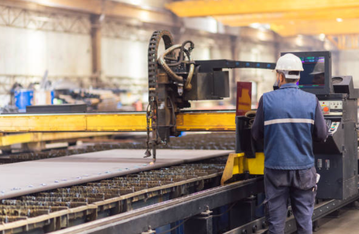 A man is standing in front of a machine in a factory.