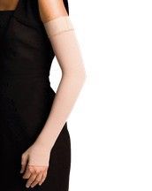 Mujer sentada en una silla moderna, con un vestido ligero estampado, tocándose el hombro.