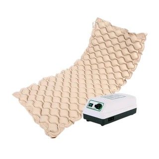 Colchón superpuesto de presión alterna de color beige con un pequeño controlador de bomba de aire blanco.