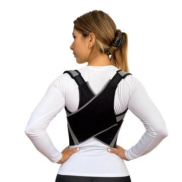 Mujer con un corsé ortopédico negro sobre una camisa blanca, vista de espaldas sobre un fondo blanco.
