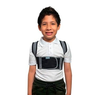Niño con un corrector postural gris sobre una camisa polo blanca sobre un fondo liso.