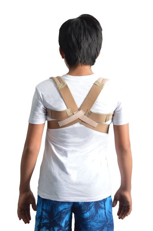 Niño sonriente con camiseta negra y mochila de color canela, de pie sobre un fondo blanco.