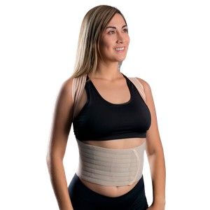 Mujer con sujetador deportivo negro y faja lumbar beige, de pie sobre un fondo blanco.