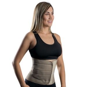 Mujer con una faja reductora beige sobre una camiseta de tirantes negra, de perfil sobre un fondo blanco.