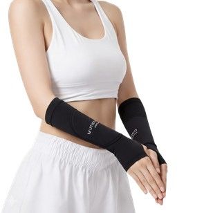 Persona que lleva mangas negras con agujeros para los pulgares y un conjunto deportivo blanco.