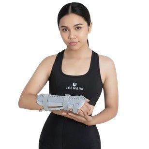 Mujer con ropa deportiva negra sosteniendo una muñequera gris sobre un fondo blanco.
