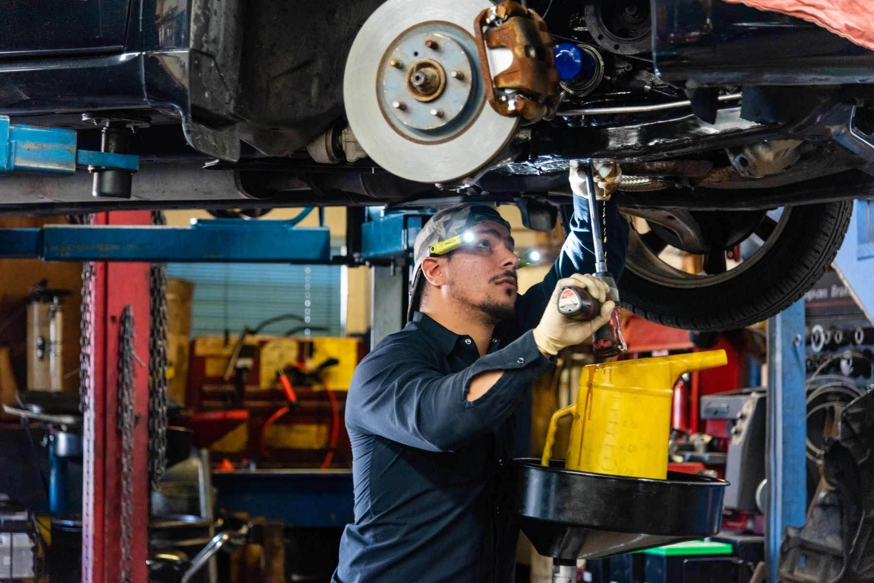 A man is working on the underside of a car in a garage. | Van Dorn Auto Repair