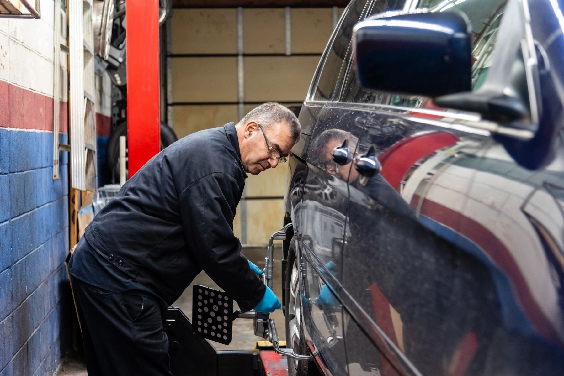 A man is working on a car wheel in a garage. | Van Dorn Auto Repair
