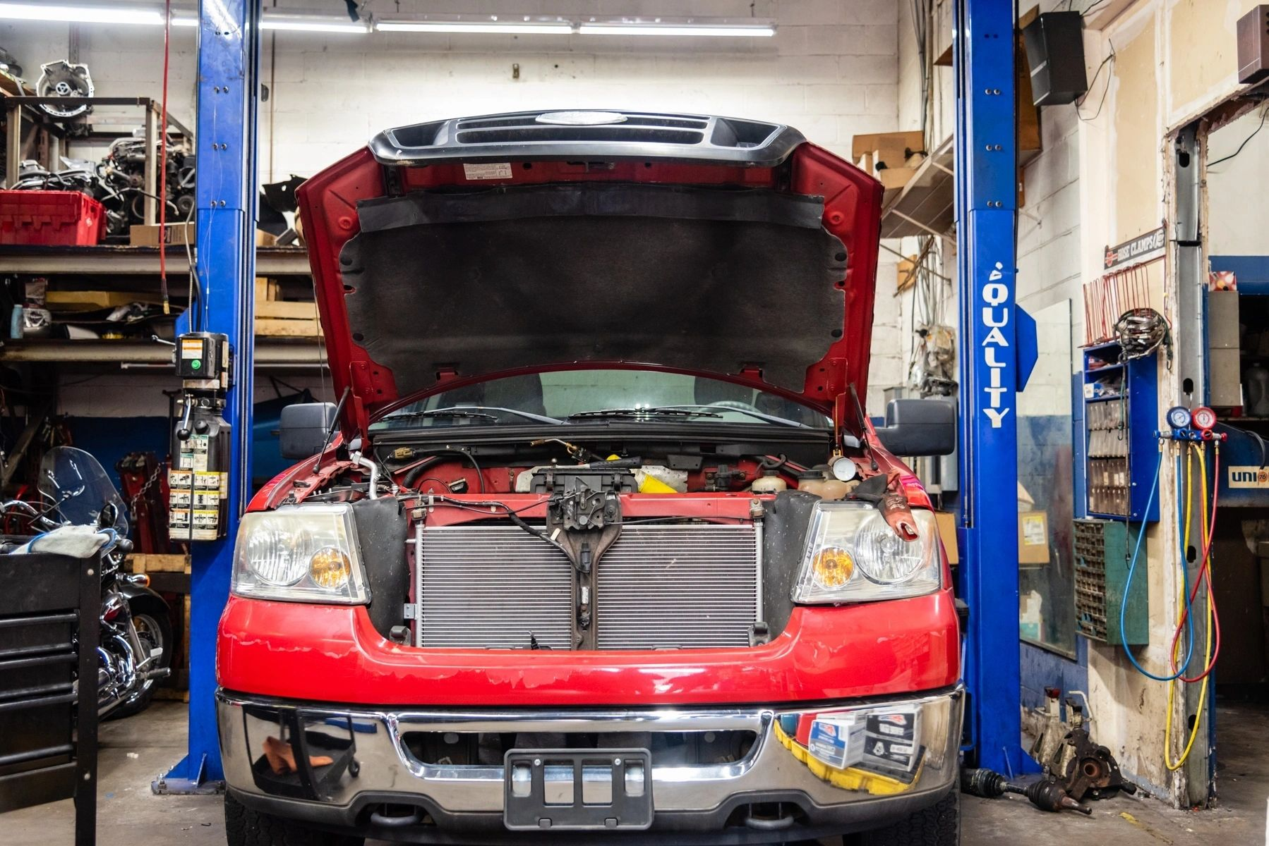 A red truck with the hood up is on a lift in a garage. | Van Dorn Auto Repair