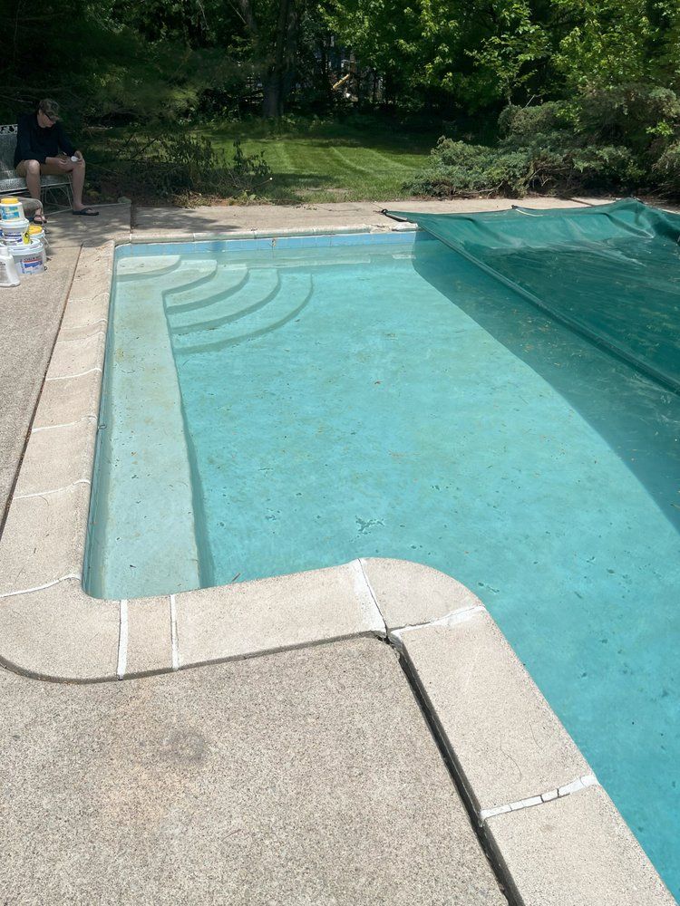 Backyard swimming pool with clear blue water and concrete deck on a sunny day