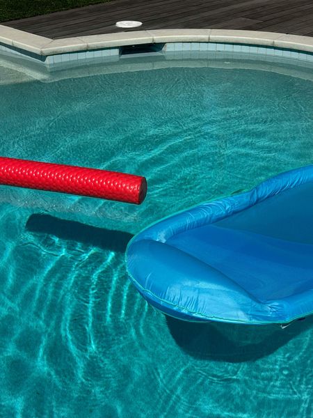 Red and blue pool floats in a swimming pool with rippling water.