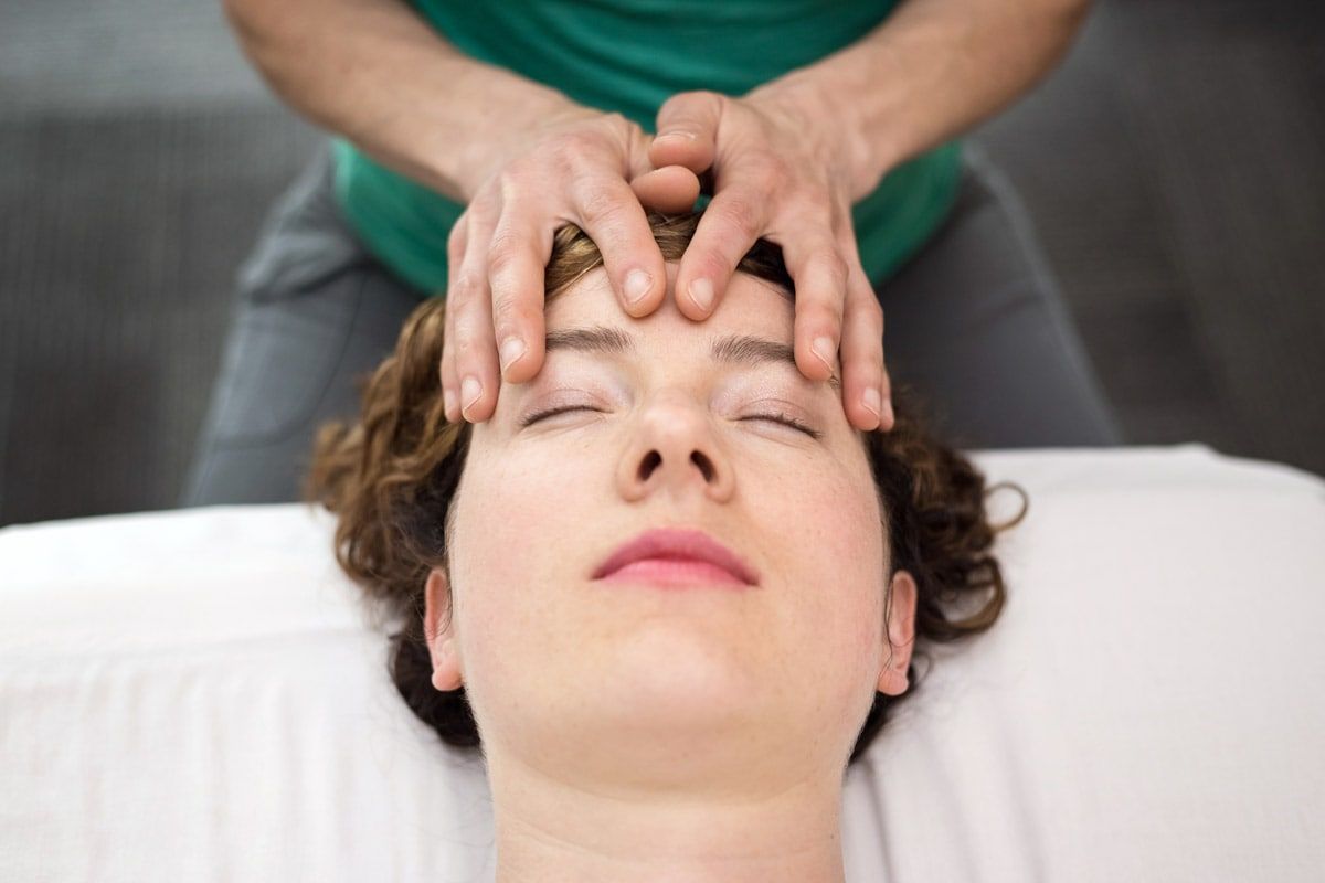 A woman is getting a head massage with her eyes closed.
