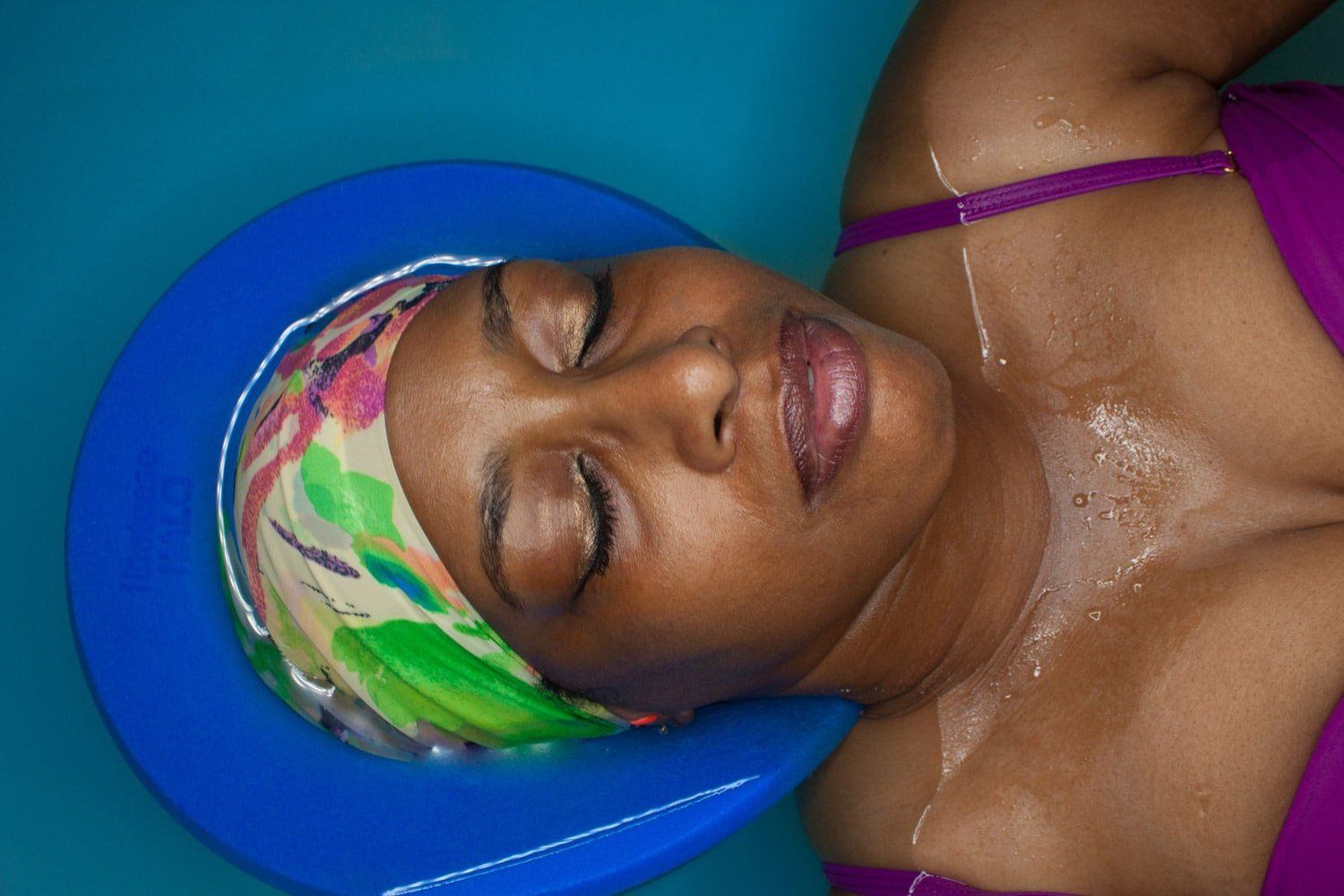 A woman is laying on a blue cushion with her eyes closed.