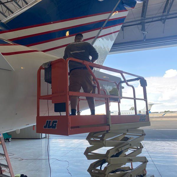 man on scissor lift cleaning plane