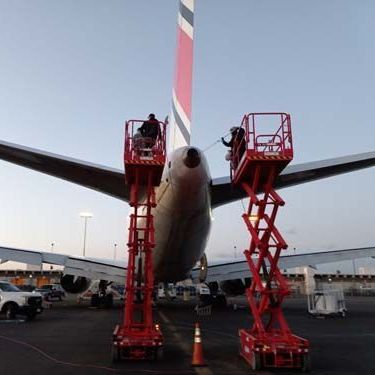 men on scissor lift cleaning plane