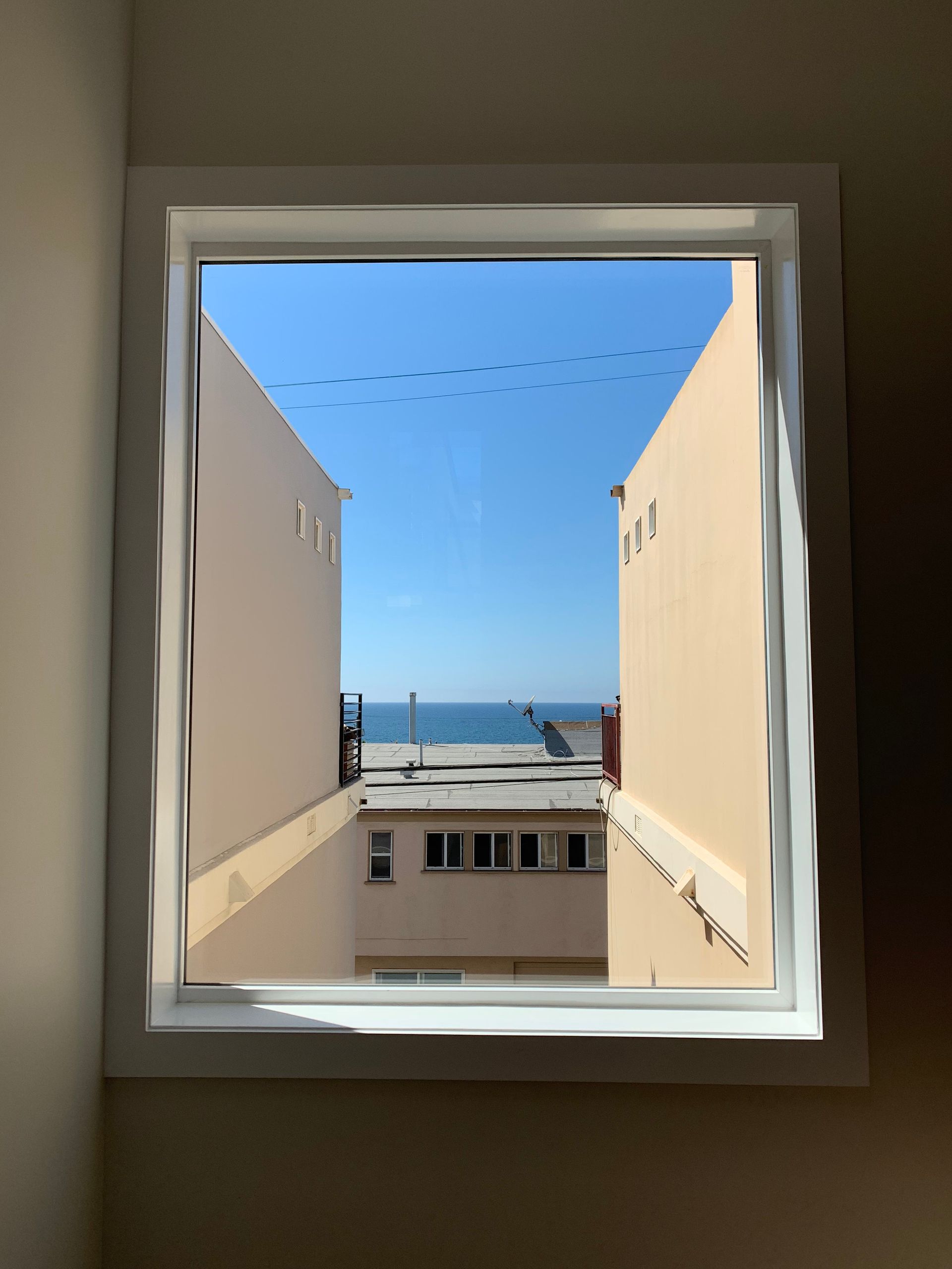 a view of the ocean through a window between two buildings