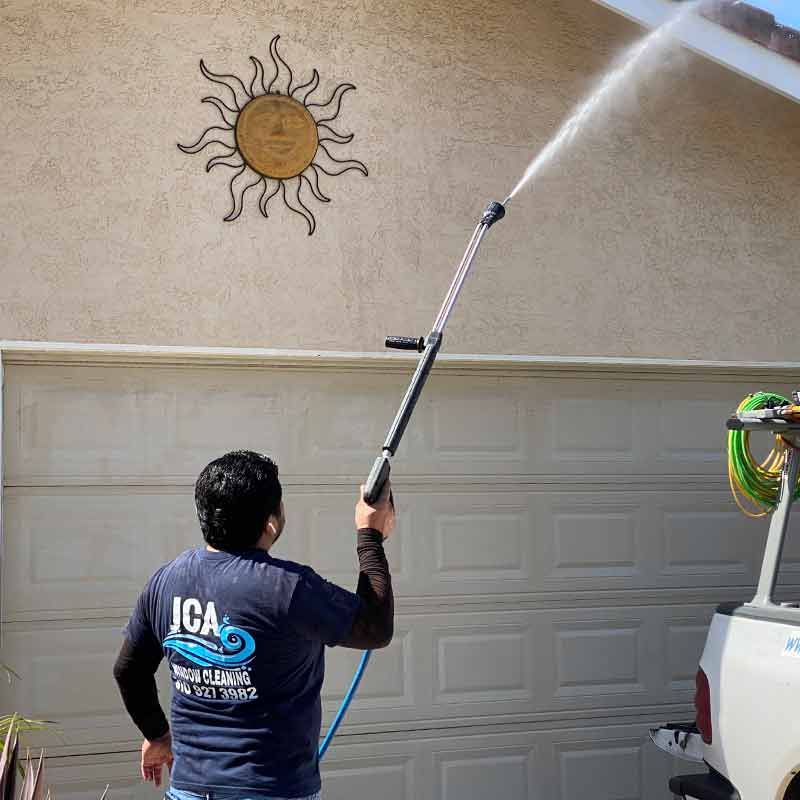 a man is using a high pressure washer to clean a garage door