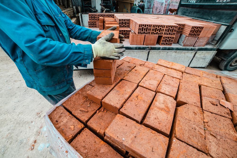 Worker Stacking Red Bricks on a Pallet — A & S Cuthel Earthmoving & Transport in Nambucca Heads, NSW