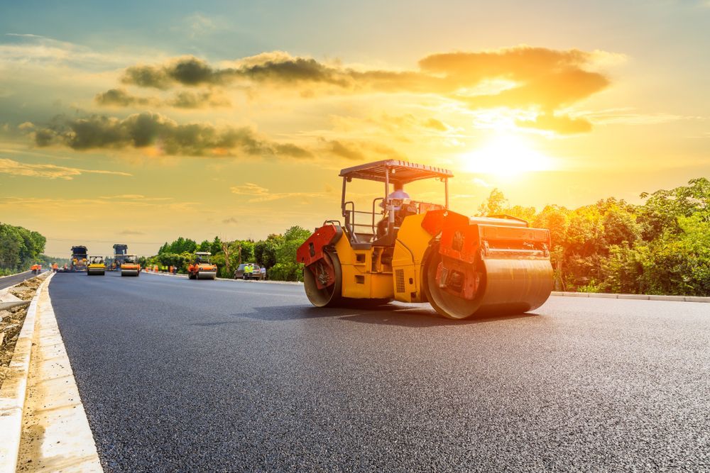 Yellow Road Roller Paving a Sunlit Highway — A & S Cuthel Earthmoving & Transport in Coffs Harbour, NSW