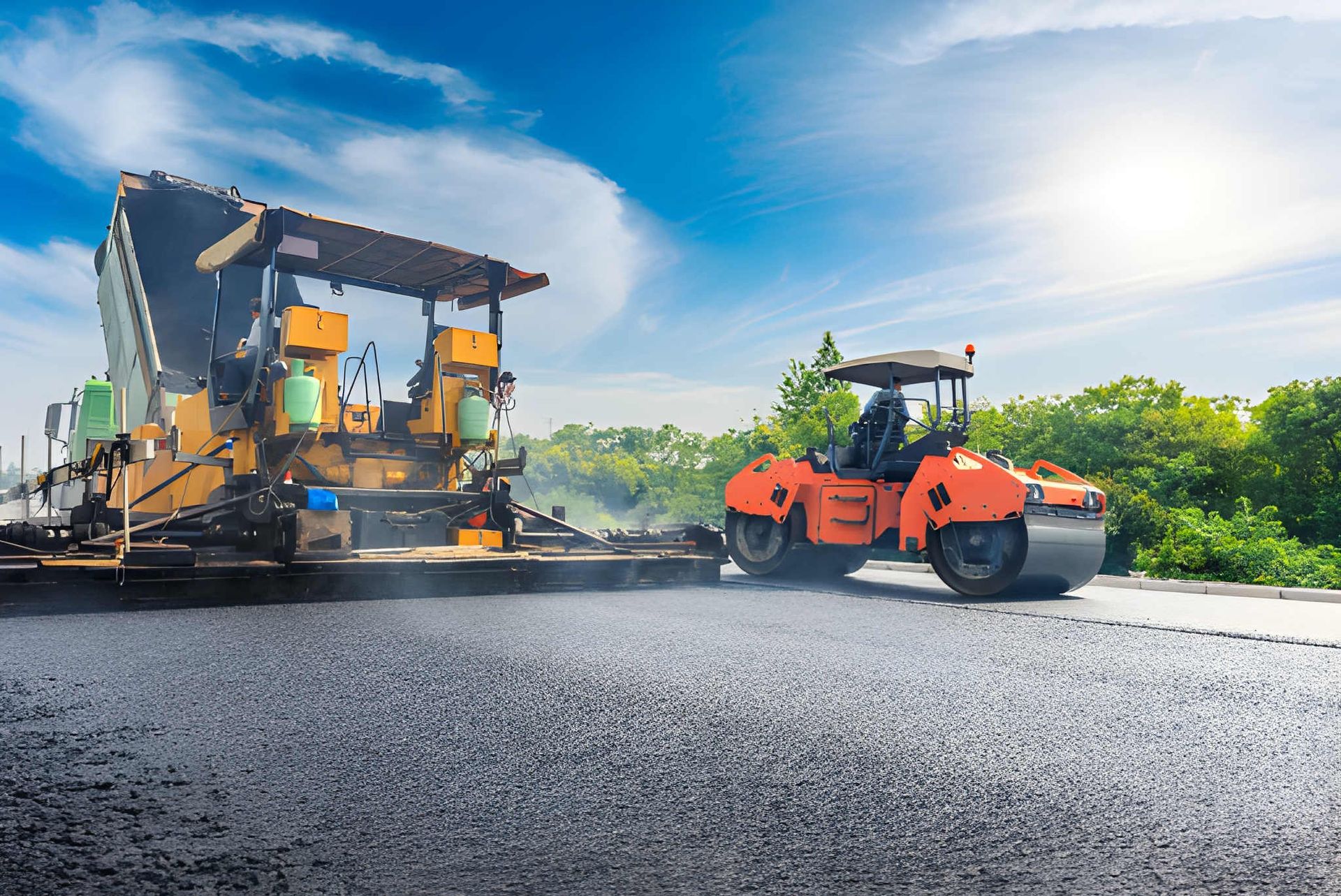 Road Paver and Orange Roller Working — A & S Cuthel Earthmoving & Transport in Dorrigo, NSW