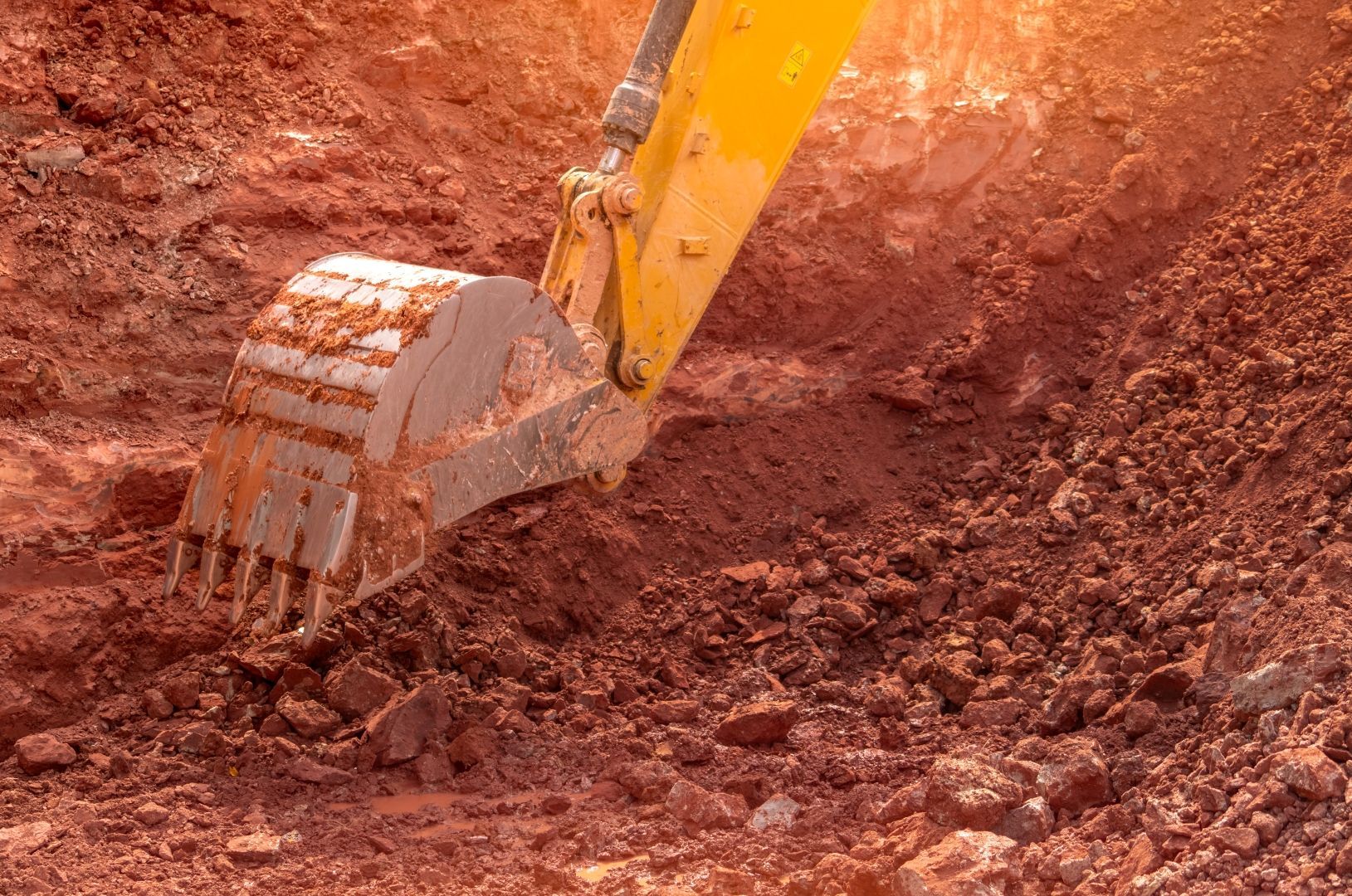 Excavator Bucket Digging Reddish Soil — A & S Cuthel Earthmoving & Transport in Grafton, NSW