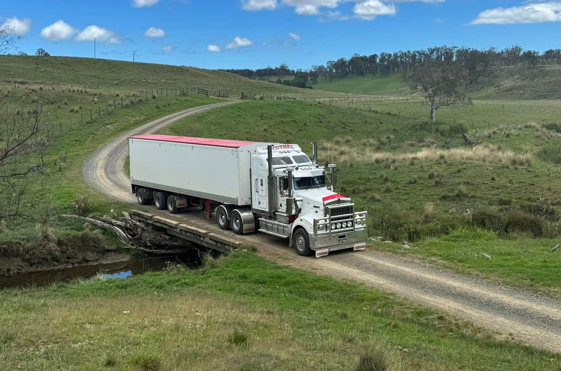 White Semi Truck Driving on A Dirt Road Through Green Hills — A & S Cuthel Earthmoving & Transport in Dorrigo, NSW